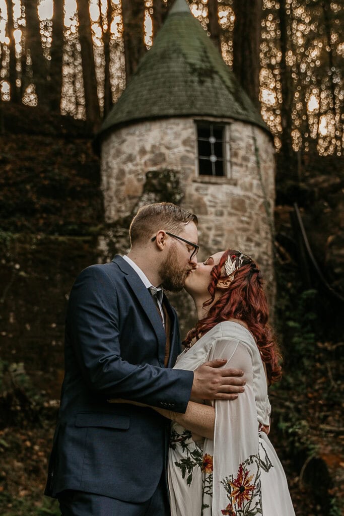 A couple kisses in front of an old stone turret during their elopement.