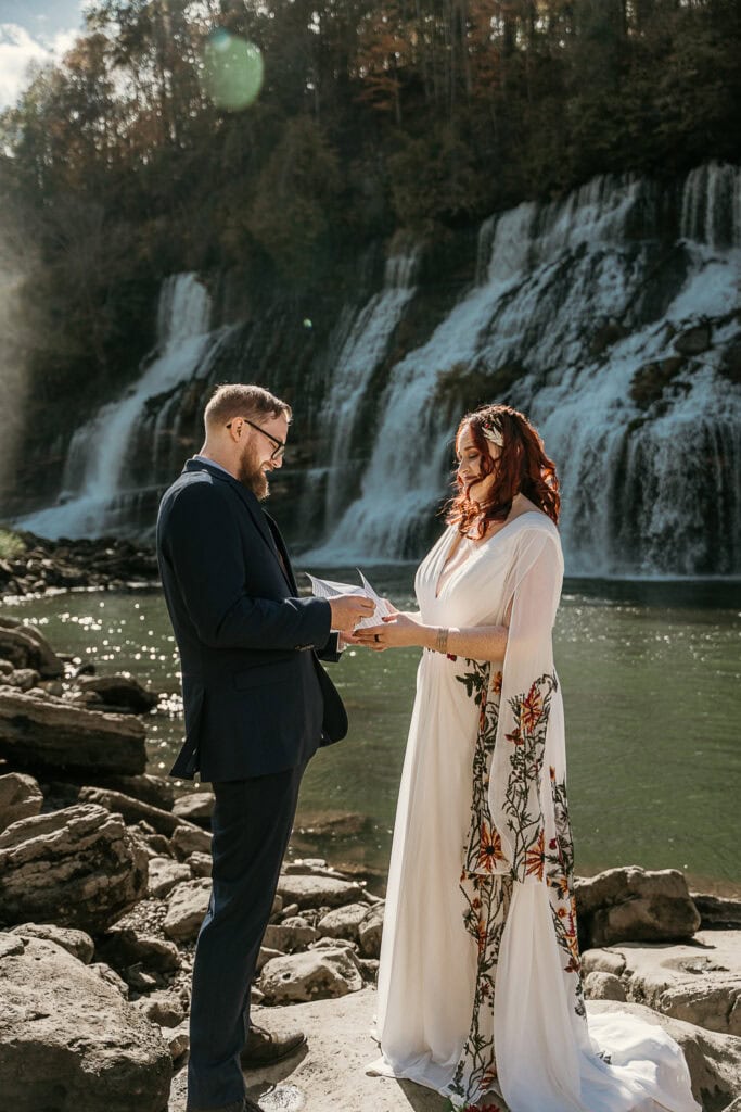 A couple exchange vows in front of a waterfall.