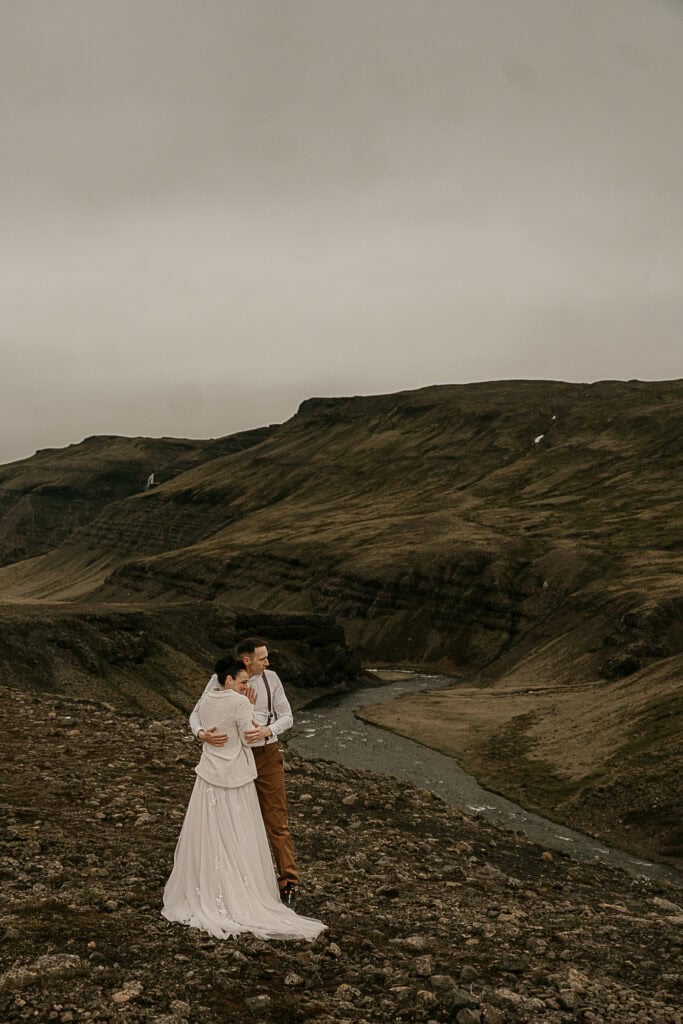 A couple overlooks a river in Iceland during their elopement.