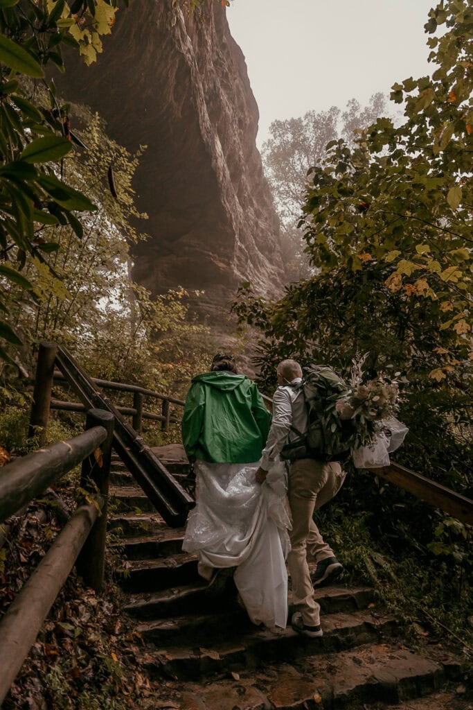 A couple climbs the stairs up to Natural Bridge on a foggy morning during their elopement.