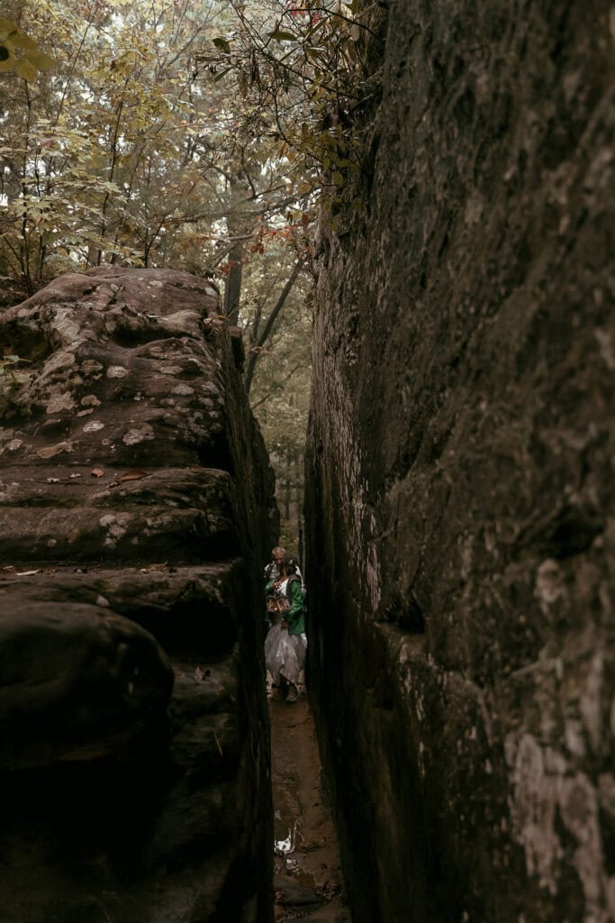 A couple in wedding attire hikes through Fat Man's Squeeze.